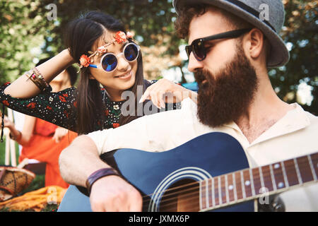 Junge boho Paar spielen akustische Gitarre bei Festival Stockfoto