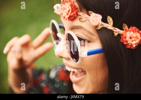 Junge Hippie Frau in floralen Stirnband Making Peace Sign an Festival Stockfoto