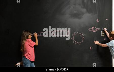 Mädchen schauen durch imaginäre Teleskop auf Tafel gezeichnet Stockfoto