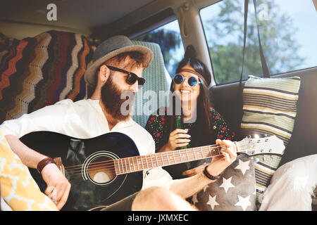 Junge boho Paar spielen akustische Gitarre in der Freizeit van Stockfoto