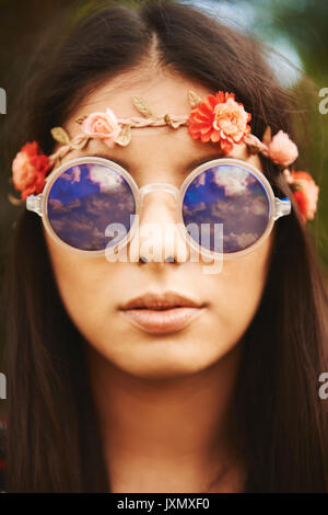 Porträt der jungen Hippy Frau in floralen Kopfbügel und Sonnenbrille bei Festival Stockfoto