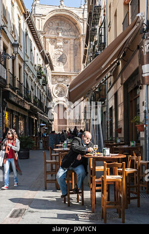 Granada, Spanien - 16. Februar 2013: Mann nimmt einen Snack auf der Straße Marques mit der Fassade der Kathedrale im Hintergrund, Granada, Spanien Stockfoto