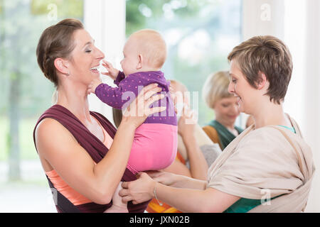 Die jungen Frauen lernen, wie man Baby Carrier für die Kinder zu verwenden Stockfoto