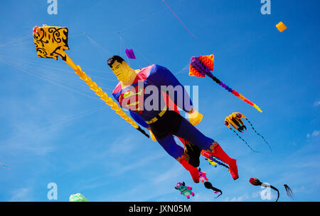 Einen Superman kite gegen einen Blu Sky fliegen neben Fisch ray Drachen Stockfoto