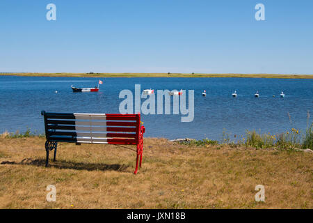 Sitzbank und Boote mit französischen Akadische Fahne in Bouctouche, New Brunswick, im Maritimes, Atlantik Kanada an einem sonnigen Tag Stockfoto
