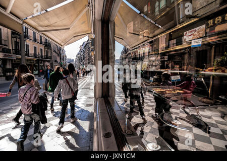 Menschen zu Fuß auf Reyes Catolicos Street und spiegelt sich in der Schaufenster der alten Konditorei Lopez Mezquita, das traditionelle Gebäck ist eine der ältesten Stockfoto
