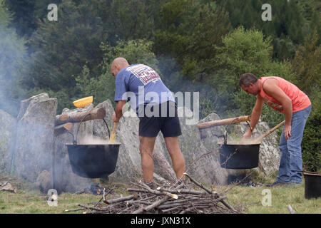 Italienische Maismehl Polenta (Brei) auf langsamen Flamme in einem Topf auf einem Holz und Kohle Feuer während eines ländlichen Mahlzeit in einem Wald gekocht Stockfoto