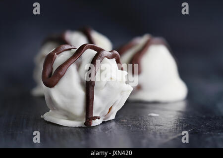 Weiße Schokolade Trüffel für Weihnachten oder Valentines Tag beträufelt mit dunkler Schokolade. Extrem flache Tiefenschärfe mit selektiven Fokus auf Süßigkeiten Stockfoto