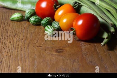 Cucamelons in selektiven Fokus mit rot und orange Tomaten und grüne Stangenbohnen auf Holz mit Kopie Raum Stockfoto