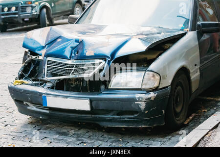 Nahaufnahme von gebrochen Stoßstange und Motorhaube oder Haube von Luxus Auto zerkratzt mit Schäden. Verlassenes Auto nach Unfall in der Stadt. Stockfoto