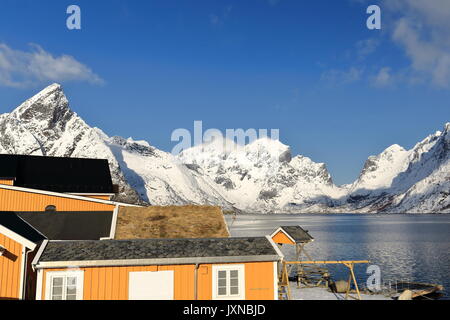 Sakrisoya Insel - gelb Cottages der Fischwirtschaft - Halterungen um Vorfjorden: Olstinden-Rostadtinden - Litlklokktinden-Klokktinden - Austervasstinden-Mol Stockfoto