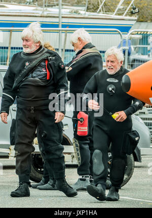 Drei ältere männliche Freunde in tauchen Anzüge, in den Hafen von Penzance, Cornwall, England, Großbritannien. Stockfoto