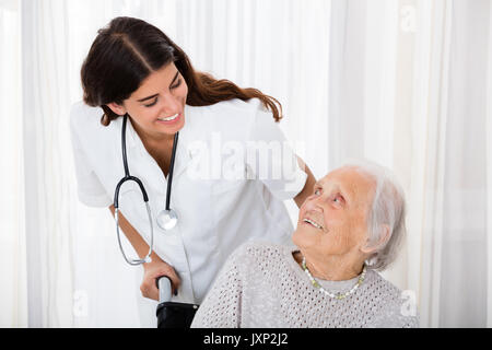 Pflege Ärztin hilft behinderten älteren Patienten im Krankenhaus Stockfoto