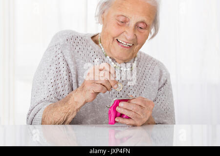 Gerne ältere Frau einfügen Münze in kleinen Geldbeutel Stockfoto