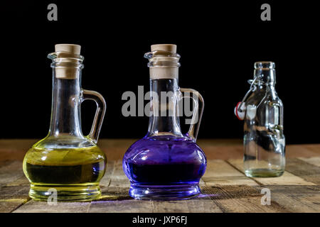 Flaschen farbige Flüssigkeit auf einer hölzernen Küchentisch. Holztisch. Schwarzer Hintergrund Stockfoto