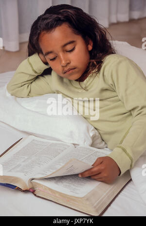 Junge Mädchen 7-10 Jahre alten Lesen der Bibel im Bett African American/Kaukasisch Myrleen Pearson Stockfoto