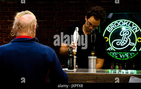 Barkeeper aus Brooklyn Brewery gießen ein Bier zu einem balding älterer Mann Stockfoto