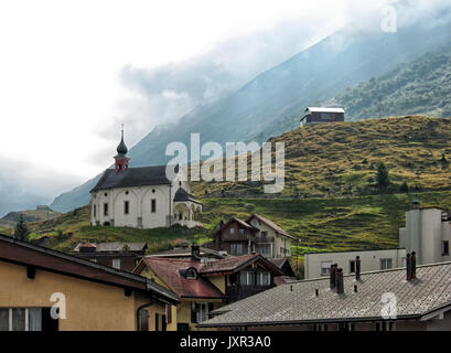 Eine alte katholische Kirche steht auf dem Berg in Andermatt in der Schweiz im Spätsommer. Stockfoto