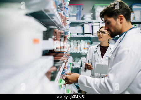 Zwei Apotheker in der Apotheke arbeiten. Männliche und weibliche Apotheker prüfen Medikamente bestand am Krankenhaus Apotheke. Stockfoto