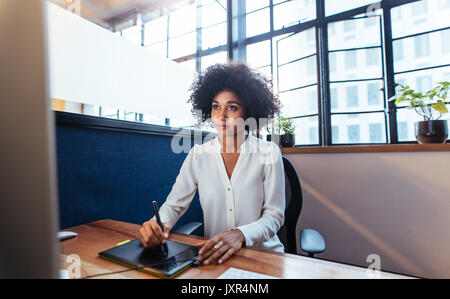 Junge weibliche Graphic Designer arbeiten am Computer mit Zeichnung Pad im Büro Schreibtisch. Junge afrikanische Frau mit Digital Graphic Tablet- und Zeichenstift f Stockfoto