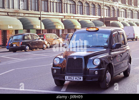 LONDON, Großbritannien - 09 Februar: Traditionelle taxi service Taxi Auto auf der Straße mit anderen Autos im Hintergrund in der Nähe von Harrods in London, Großbritannien Stockfoto