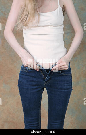 Junge Mädchen, das versuchte bis zu zip enge blaue Jeans Stockfoto