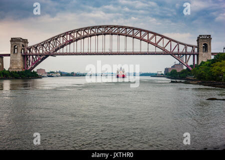 Red cargo Schiff segeln unter der Hell Gate Brücke über den East River, Astoria Park, New York City Stockfoto