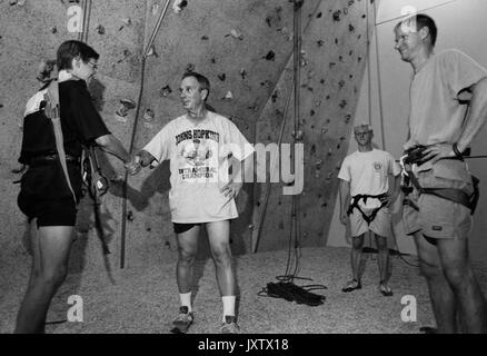 Michael Rubens Bloomberg, freimütiger Schuss, Bloomberg steht mit drei Instruktoren vor einer Kletterwand, Bloomberg schüttelt mit einem der Instruktoren, ca. 47 Jahre alt, 1997 die Hand. Stockfoto