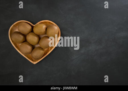 Sammlung frische Kiwi in Herzform Holzplatte auf Tafel mit hohen Winkel Foto isoliert. Stockfoto