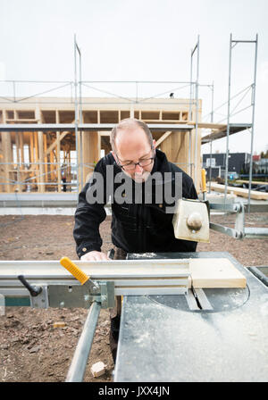 Tischler mit Tisch sah zu schneiden Holz am Standort Stockfoto