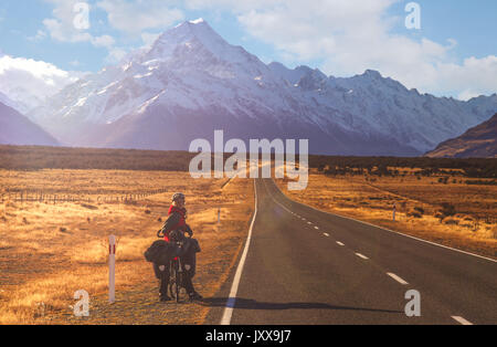 Frau auf einem Fahrrad Reise auf einer Straße, die zu den Mount Cook, den höchsten Gipfel in Neuseeland Stockfoto