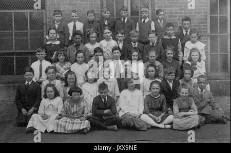 Ganzkörperaufnahme von Schulkindern, sitzend und stehend im Freien, einige Afrikanerin, 1920. Stockfoto