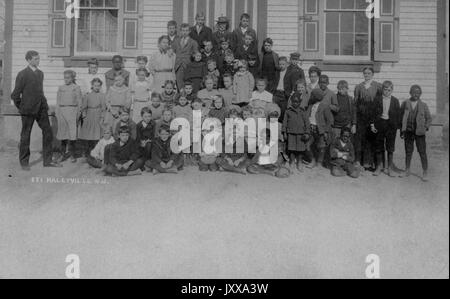 Ganzkörperaufnahme von Schulkindern, einige sitzend, einige stehend, einige afroamerikanisch, im Freien; Haleyville, New Jersey, 1915. Stockfoto