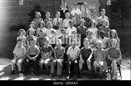 Ganzkörperaufnahme von Schulkindern, sitzend, ein afroamerikanisches Mädchen in der zweiten Reihe, 1920. Stockfoto