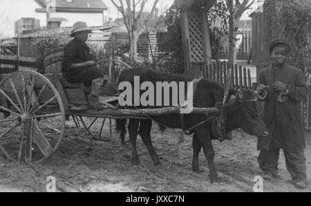 Ganzkörperportrait von zwei jungen afroamerikanischen Jungen, einer in einem Pferd und Buggy sitzend, ein anderer stehend; liest: 'Wahrscheinlich: Schleppen Mops schwarze Kinderarbeit', 1920.