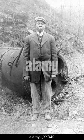 Ganzkörperporträt eines in Uniform gekleideten afroamerikanischen Militärs, im Freien mit Kriegsmaschinerie hinter sich, neutraler Gesichtsausdruck, 1917. Stockfoto