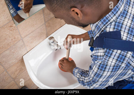 Nahaufnahme der Klempner Hand mit Kolben im Waschbecken im Bad Stockfoto