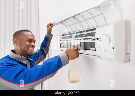 Lächelnd männlichen Techniker Reinigung Klimaanlage zu Hause Stockfoto