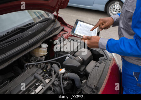 Nahaufnahme der Mechaniker mit digitalen Tablet Übersicht Diagramm während der Prüfung Auto Stockfoto