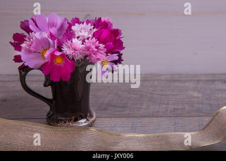 Ein Bouquet von rosa und lila Blumen cosmea oder Cosmos mit Band auf rustikalen hölzernen Brettern. Kopieren Sie Platz. Mutter, Valentines, Frauen, Hochzeit Konzept Stockfoto