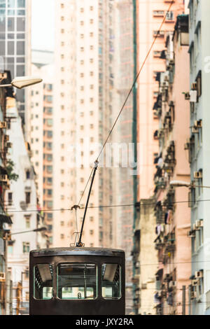 Blick auf hohe Häuser an der Straße in Hongkong und Oberdeck der Straßenbahn mit Stromabnehmer und Fahrdraht Stockfoto