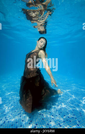 Junge schöne Frau in Kleid posiert unter Wasser im Pool