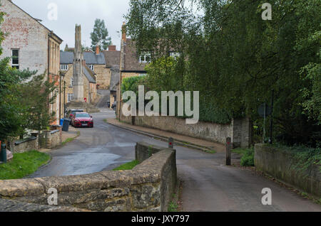 Ansicht von einem Steg in der High Street mit einer Königin Eleanor Kreuz in der Entfernung, Geddington, Northamptonshire, Großbritannien Stockfoto