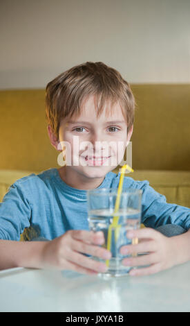 7-jähriger Junge Trinkwasser durch einen Strohhalm Stockfoto