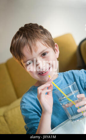 7-jähriger Junge Trinkwasser durch einen Strohhalm Stockfoto