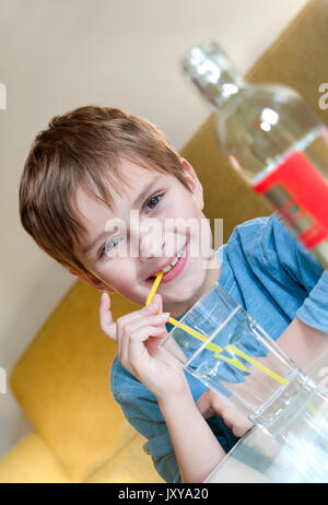 7-jähriger Junge Trinkwasser durch einen Strohhalm Stockfoto