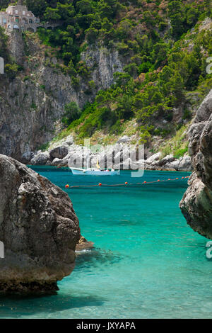 Segelboot günstig in einer felsigen Bucht auf der Insel Capri, Golf von Neapel, Kampanien, Italien Stockfoto