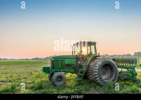 Traktor in einem Feld in einem ländlichen Maryland Farm bei Sonnenuntergang mit Sonnenstrahlen. Stockfoto