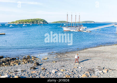 Bar Harbor, USA - Juni 8, 2017: eine Frau, die zu Fuß auf felsigen Strand mit Booten im Sommer Dorf im Urlaub Stockfoto