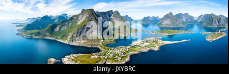 Antenne Panoramablick auf Reine traditionelle Fischerdorf in der Lofoten Inseln im nördlichen Norwegen mit blauem Meer und Berge während der sonnigen arcti Stockfoto